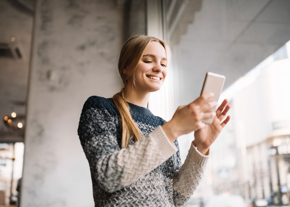 Pulvital Online Cashback – bares Geld bei jedem Online-Einkauf Lächelnde Frau sitzt mit Laptop und Kreditkarte auf dem Sofa und nutzt Pulvital Online Cashback beim Shopping